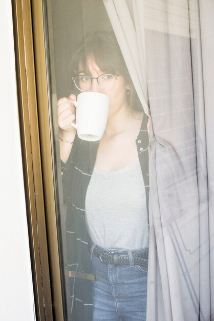 窓から見えるコーヒーを飲む女性