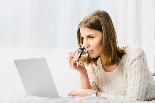 Woman drinking coffee near laptop