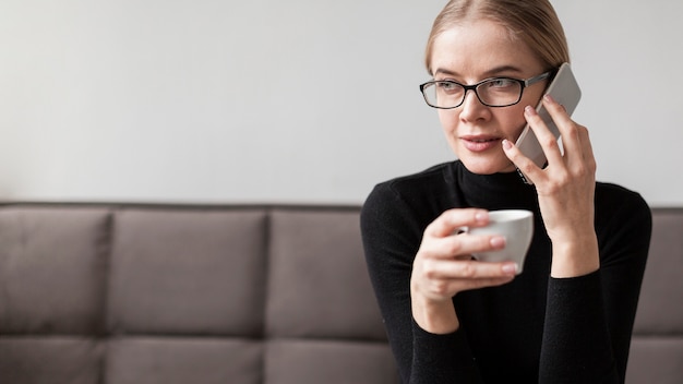 コーヒーを飲みながら電話で話している女性