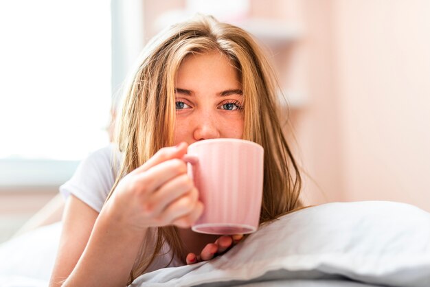 ベッドに敷設しながらコーヒーを飲む女性
