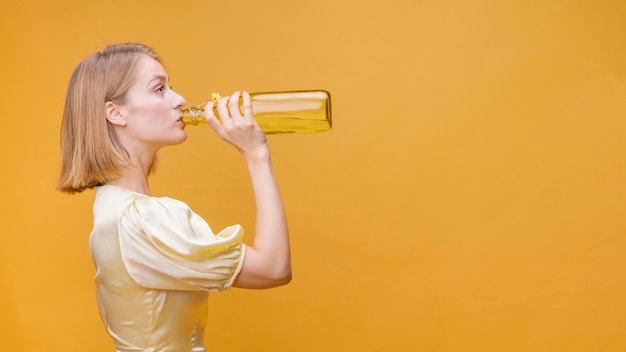 Woman drinking from bottle in a yellow scene