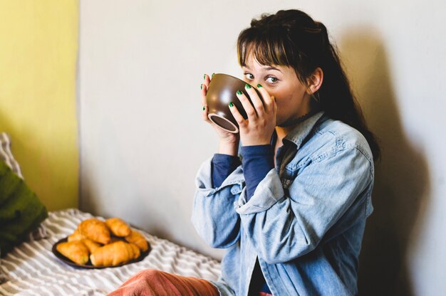 Woman drinking from bowl on bed