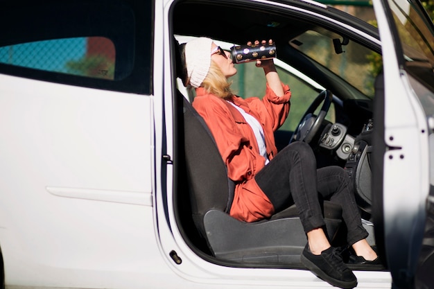 Donna che beve dal thermos in auto