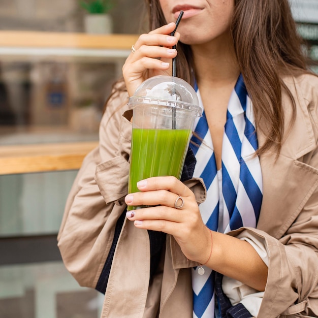 Женщина пьет зеленый коктейль