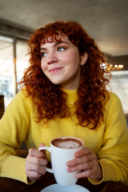 Free photo woman drinking hot chocolate at cafe