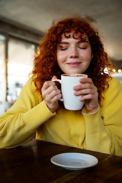 Free photo woman drinking hot chocolate at cafe