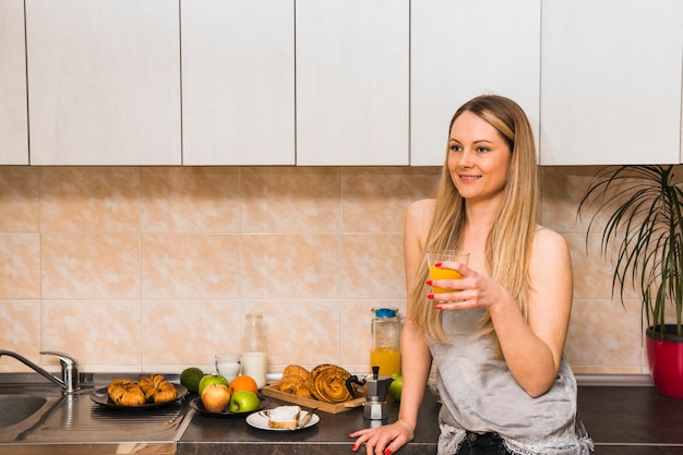 Foto gratuita donna che beve il succo in cucina