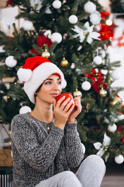 クリスマスツリーでお茶を飲む女性