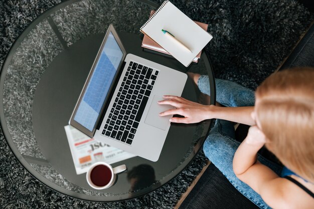 Woman drinking tea and using laptop at home