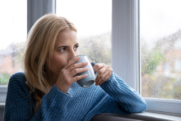 雨が降っている間にお茶を飲む女性