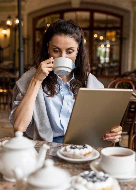 Woman drinking tea while looking on a tablet