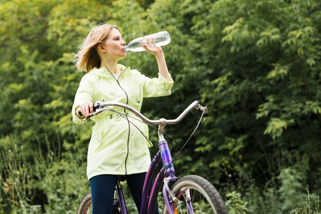 Женщина пьет воду на велосипеде