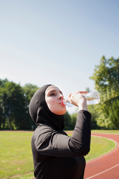 Foto gratuita acqua potabile della donna dalla bottiglia di plastica