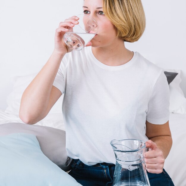 Woman drinking water near pillows