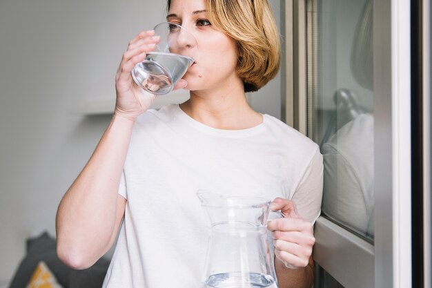 Woman drinking water near window
