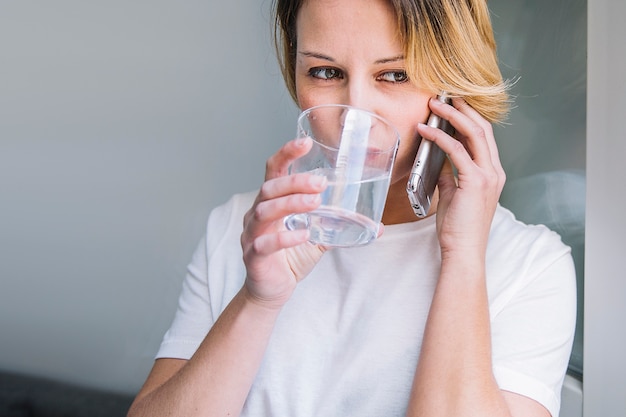 Woman drinking water and speaking on phone