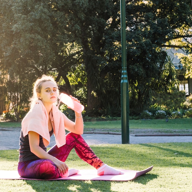 Woman drinking water on stretching mat