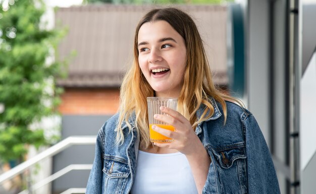 Woman drinks orange juice in a cafe closeup