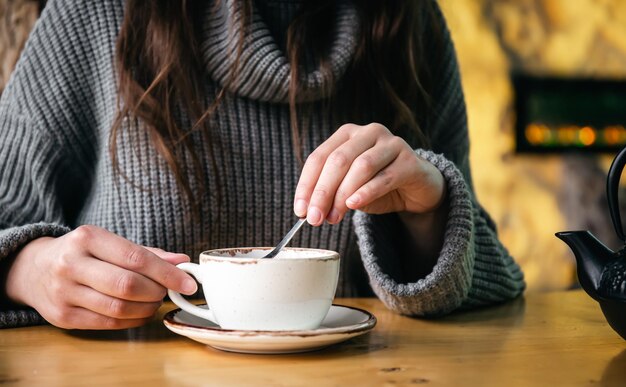 A woman drinks tea stirs sugar with a spoon