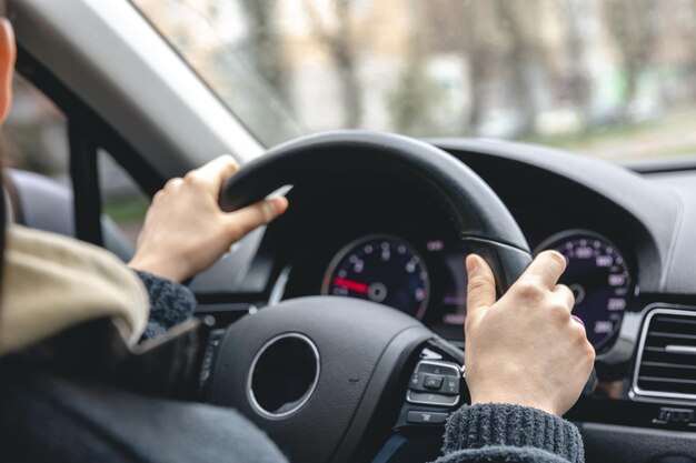 Woman drivers hands on a car steering wheel