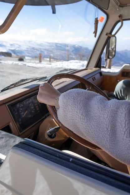 Woman driving a camper van during winter trip