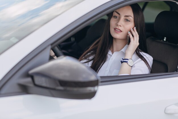 전화 통화하는 동안 차를 운전하는 여자