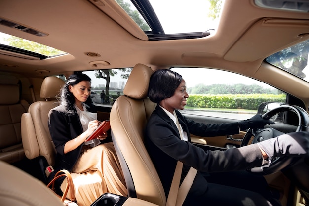 Woman driving her taxi cab with her client on the backseat