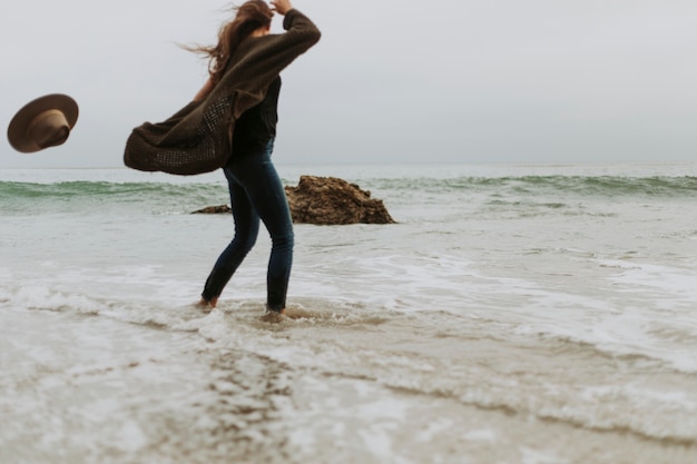 La donna lascia cadere il cappello a causa del vento in spiaggia