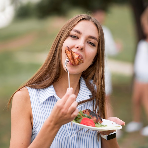 Foto gratuita donna che mangia barbecue all'aperto