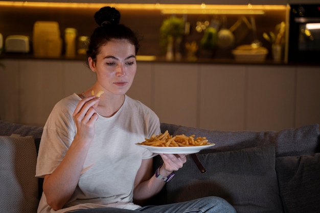 Женщина ест фаст-фуд во время просмотра фильма