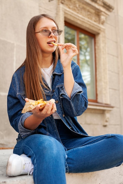 屋外でフライドポテトを食べる女性