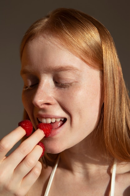 Woman eating fresh raspberry side view