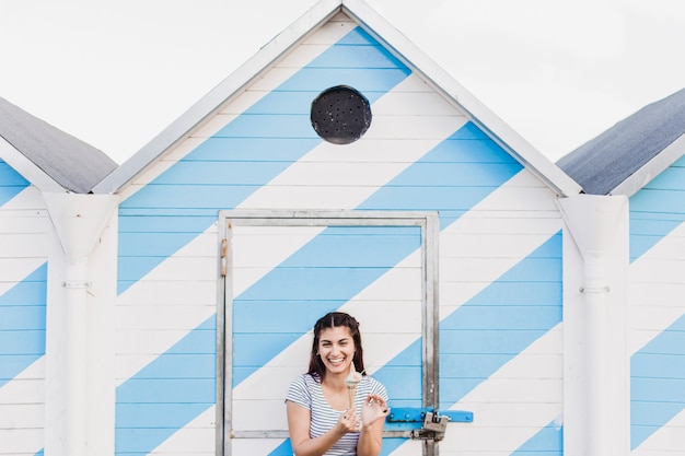 Woman eating ice cream in front of wooden house at the beach