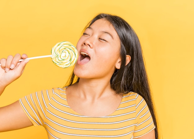 目を閉じてロリポップを食べる女性