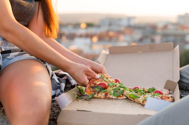 Женщина ест пиццу на открытом воздухе