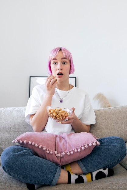 Foto gratuita donna che mangia popcorn mentre guarda un videogioco