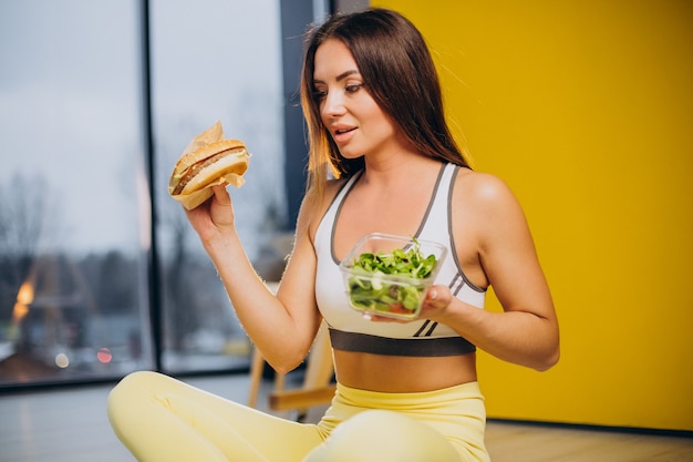 Woman eating salad isolated on yellow background