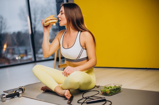 Woman eating salad isolated on yellow background