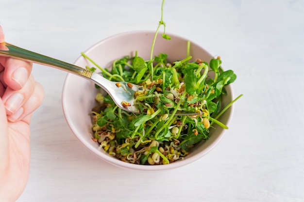Woman eating a salad made of peas microgreen sprouts and sprouted beans. vegan healthy food.