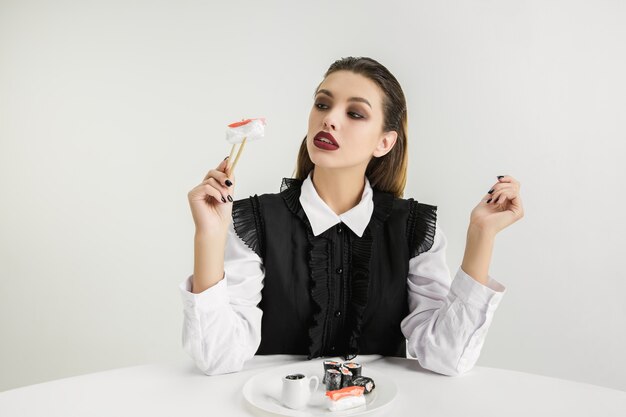 Woman eating sushi made of plastic, eco concept.