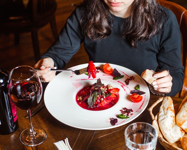 Donna che mangia insalata di pomodoro in succo rosso con noci ed erbe