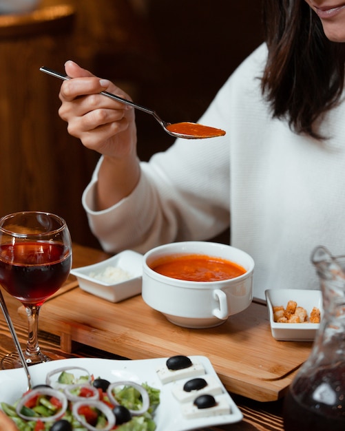 パン詰め、ワインのグラスとトマトのスープを食べる女