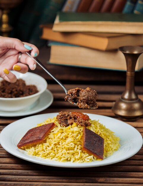 Woman eating traditional govurma plov with a spoon.