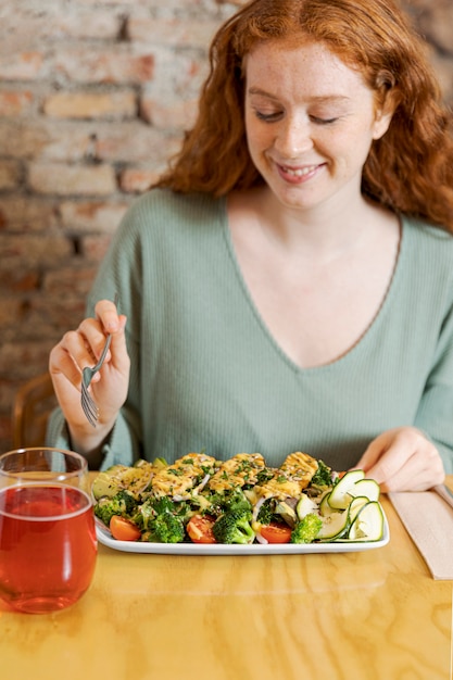 ベジタリアン料理のミディアムショットを食べる女性