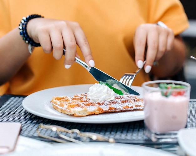 クリーム1をトッピングしたワッフルを食べる女性