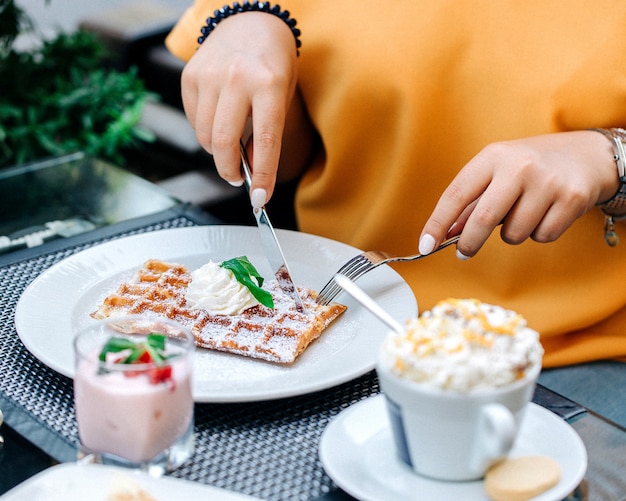 クリームをトッピングワッフルを食べる女性