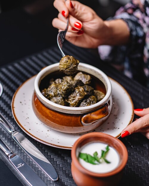 Woman eats azerbaijani grape leaves dolma served with yogurt