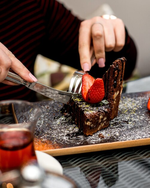 女性は上にイチゴのスライスとチョコレートケーキを食べる