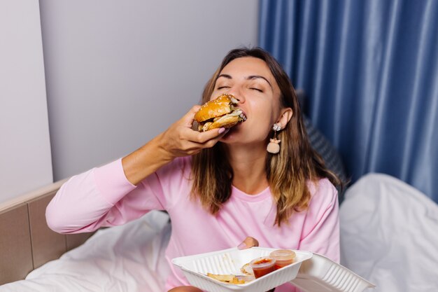 Woman eats hamburger at home