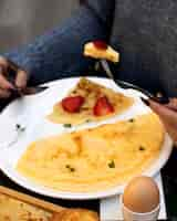 Foto gratuita la donna mangia frittata e crepe con fragole